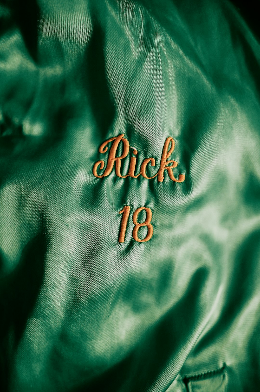 close up of a green jacket with the name rick and numer 18 stiched in yellow thread